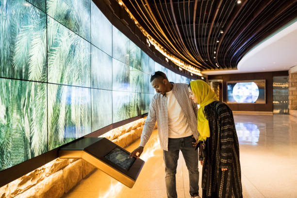 two adults using a touchscreen in a museum to learn