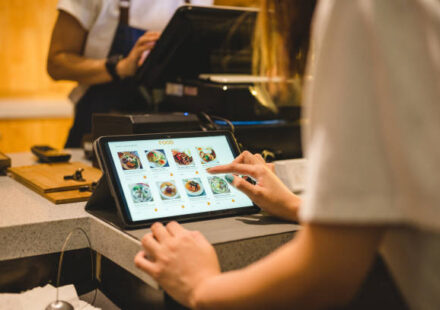 A worker using a touchscreen to take someone's order in a restaurant